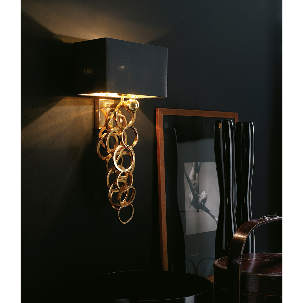 Iron wall lamp with golden, hand soldered rings.
Rectangular black chintz lampshade with golden inside.